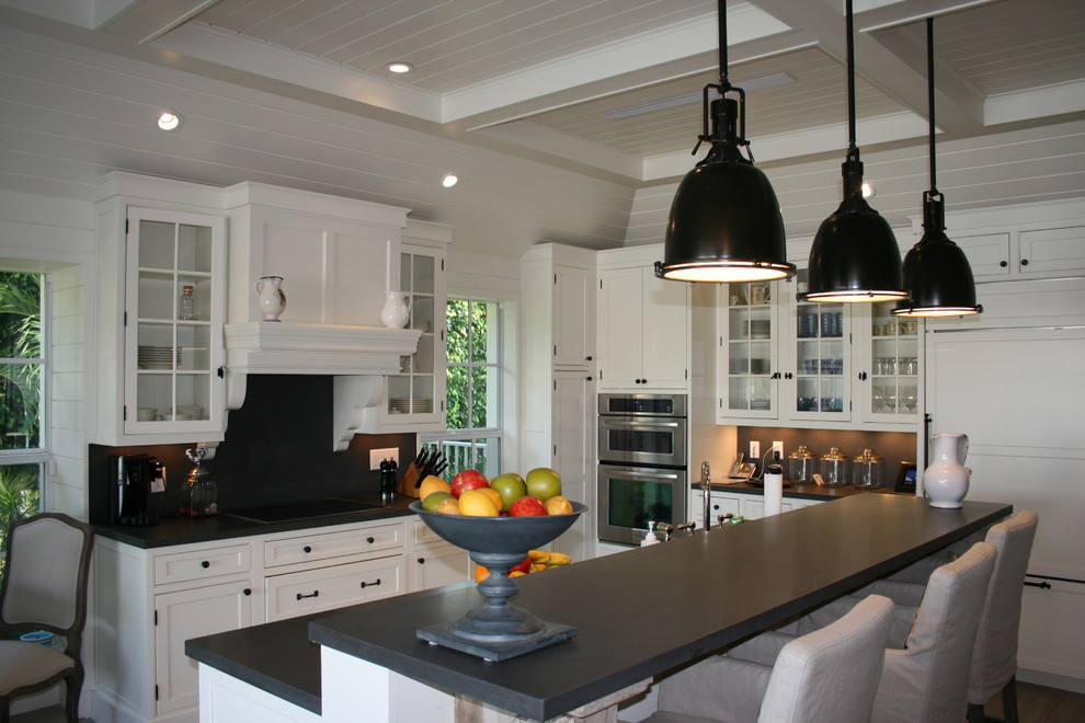 Mid-sized country u-shaped open plan kitchen in Miami with a farmhouse sink, white cabinets, panelled appliances, medium hardwood floors, with island, recessed-panel cabinets, black splashback and brown floor.