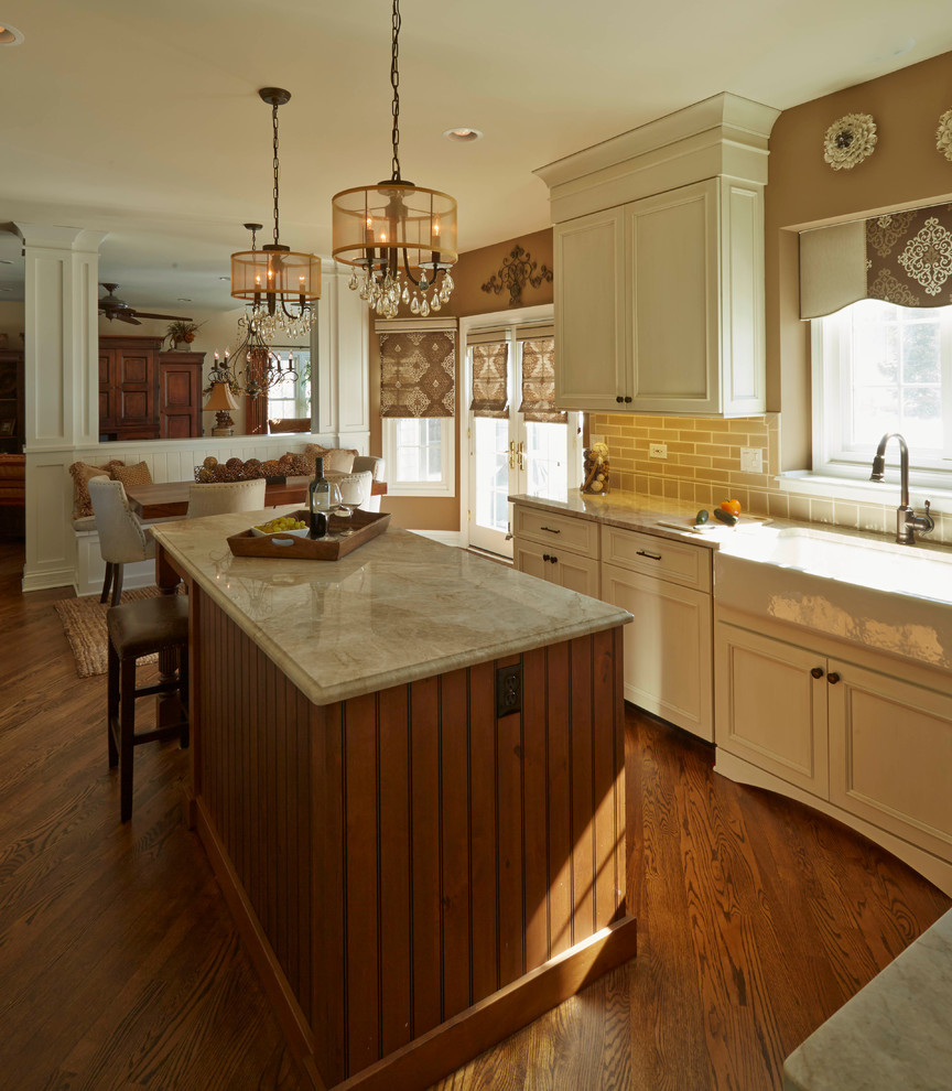 Eat-in kitchen - mid-sized transitional u-shaped medium tone wood floor eat-in kitchen idea in Tampa with a farmhouse sink, white cabinets, quartzite countertops, beige backsplash, ceramic backsplash, paneled appliances and an island