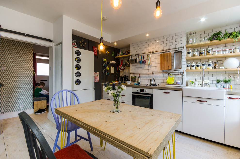 Photo of a small eclectic eat-in kitchen in London with light hardwood floors.