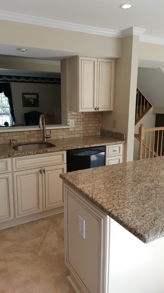 Photo of a mid-sized traditional l-shaped kitchen in DC Metro with raised-panel cabinets, beige cabinets, granite benchtops, beige splashback, stone tile splashback, black appliances, porcelain floors and with island.