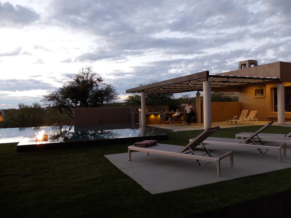 Photo of a large contemporary backyard rectangular infinity pool in Phoenix with a hot tub and concrete pavers.