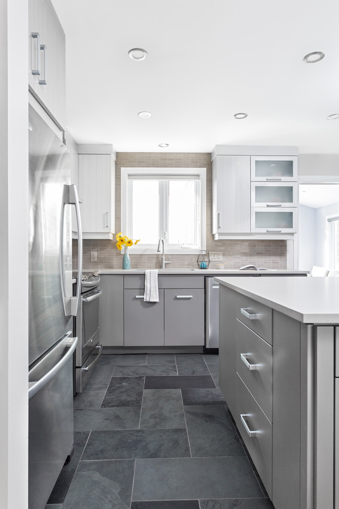 This is an example of a mid-sized modern l-shaped eat-in kitchen in Ottawa with an undermount sink, flat-panel cabinets, grey cabinets, quartz benchtops, grey splashback, porcelain splashback, stainless steel appliances, slate floors, with island and black floor.