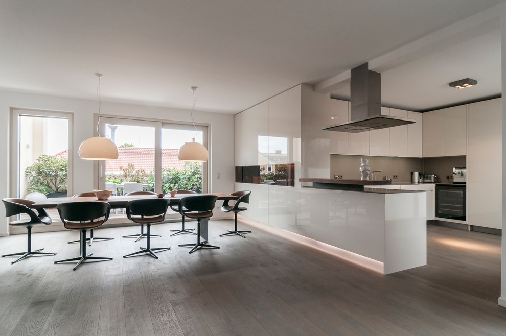 Photo of a large contemporary kitchen/dining combo in Munich with white walls and light hardwood floors.