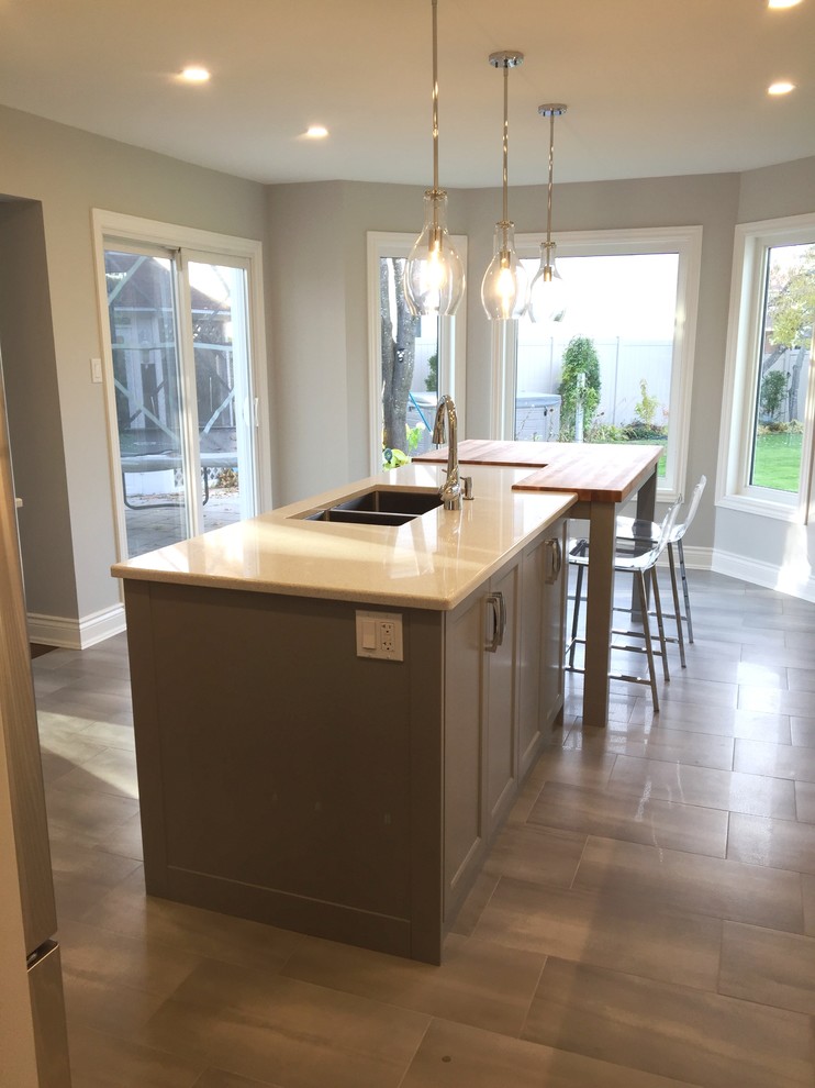 Inspiration for a large transitional u-shaped ceramic tile eat-in kitchen remodel in Ottawa with an undermount sink, shaker cabinets, white cabinets, gray backsplash, subway tile backsplash, stainless steel appliances, an island and quartzite countertops