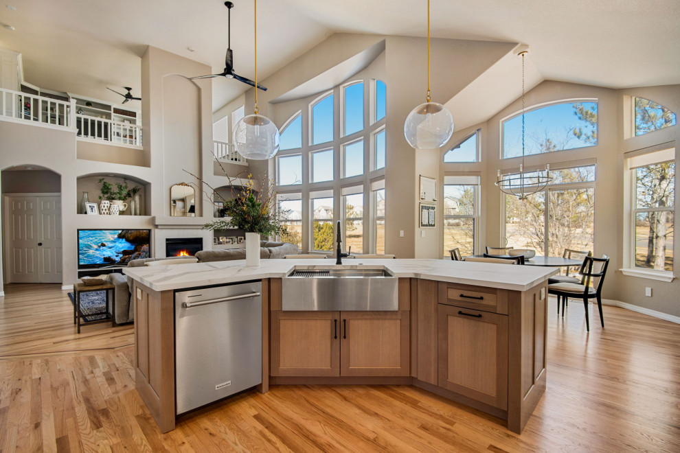 Large country l-shaped open plan kitchen in Denver with a farmhouse sink, recessed-panel cabinets, light wood cabinets, quartz benchtops, white splashback, engineered quartz splashback, stainless steel appliances, light hardwood floors, with island, beige floor and white benchtop.