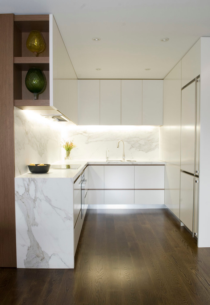 This is an example of a small modern u-shaped kitchen in Sydney with white cabinets, marble benchtops, no island, panelled appliances, white splashback and dark hardwood floors.