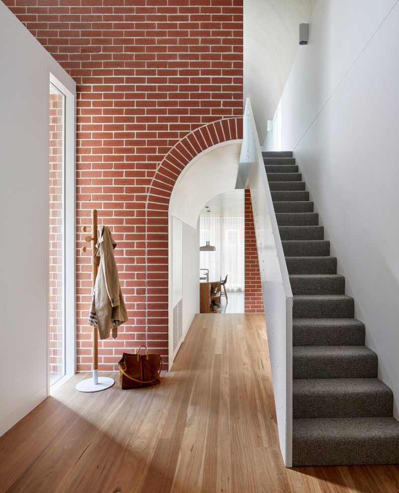 This is an example of a large contemporary carpeted straight staircase in Melbourne with carpet risers and wood railing.
