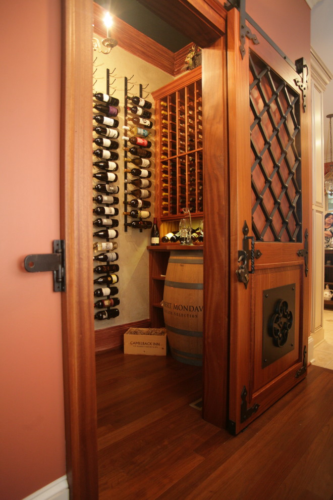 Photo of a mid-sized mediterranean wine cellar in Other with brown floor, medium hardwood floors and storage racks.