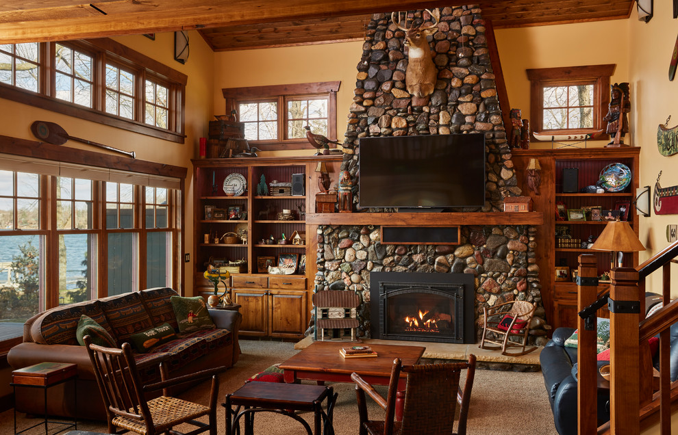 Design ideas for a mid-sized country open concept family room in Minneapolis with beige walls, carpet, a standard fireplace, a stone fireplace surround, beige floor and a wall-mounted tv.
