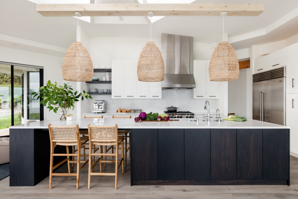 This is an example of a medium sized contemporary open plan kitchen in Other with flat-panel cabinets, dark wood cabinets, engineered stone countertops, white splashback, engineered quartz splashback, stainless steel appliances, porcelain flooring, an island, white worktops and a vaulted ceiling.