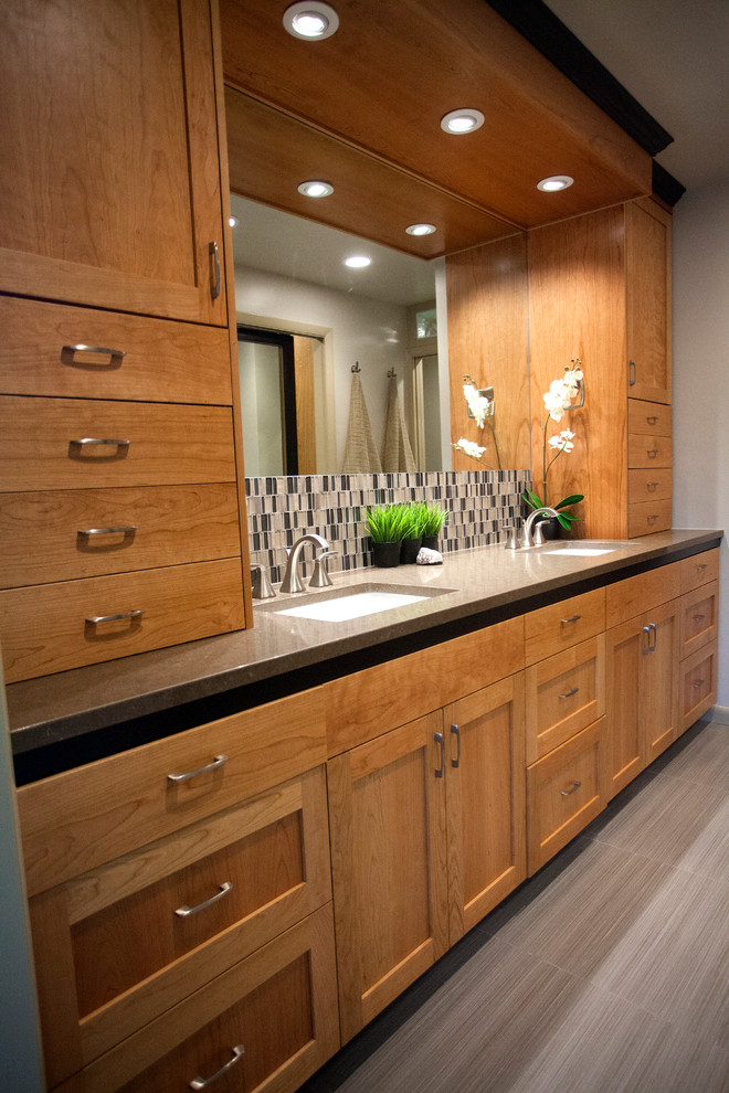 This is an example of a mid-sized contemporary master bathroom in Salt Lake City with shaker cabinets, light wood cabinets, a drop-in tub, a shower/bathtub combo, a one-piece toilet, multi-coloured tile, mosaic tile, grey walls, porcelain floors, a drop-in sink and quartzite benchtops.