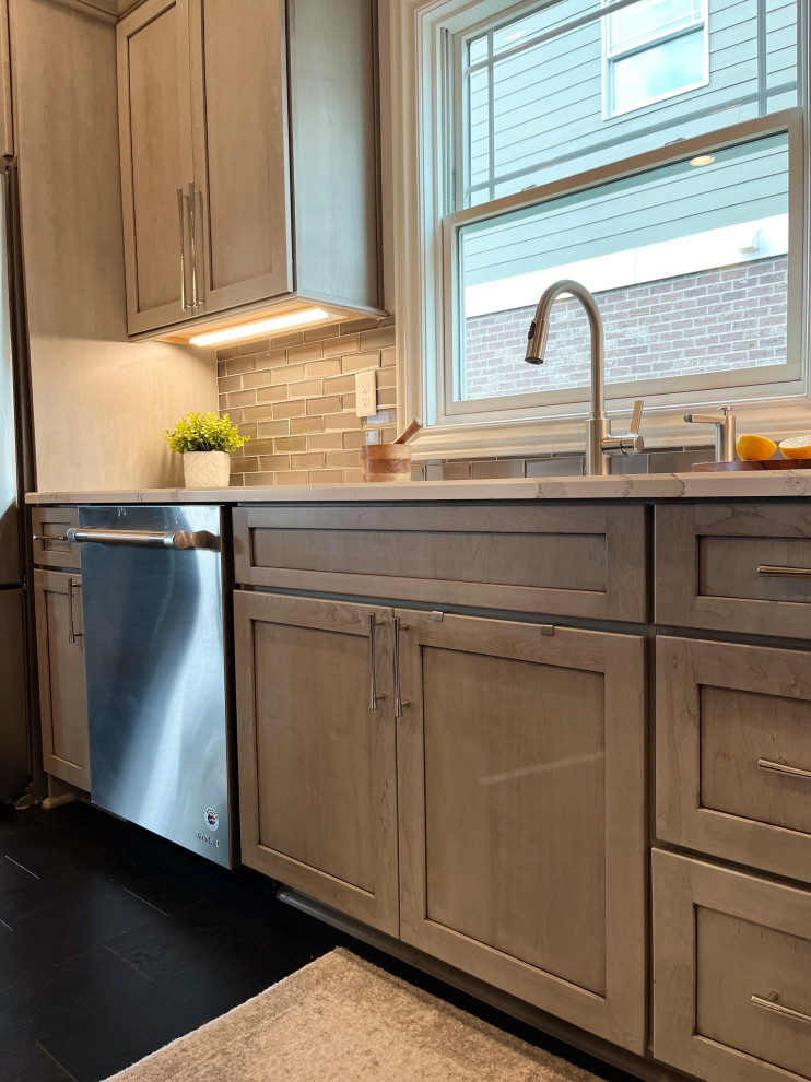 Mid-sized transitional l-shaped dark wood floor and brown floor eat-in kitchen photo with an undermount sink, gray cabinets, quartz countertops, glass tile backsplash, stainless steel appliances, an island, white backsplash and beige countertops