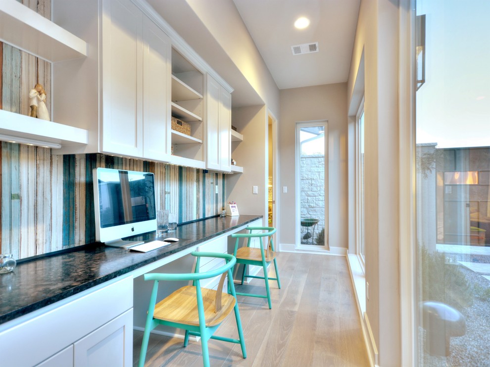 Trendy built-in desk light wood floor study room photo in Austin with beige walls
