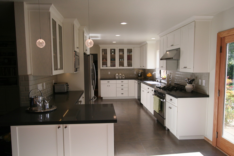 This is an example of a mid-sized traditional u-shaped eat-in kitchen in San Francisco with an undermount sink, recessed-panel cabinets, beige cabinets, laminate benchtops, grey splashback, ceramic splashback, stainless steel appliances and travertine floors.