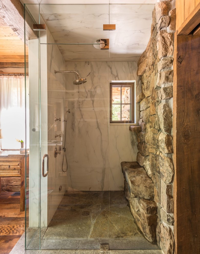 Example of a mountain style master marble tile bathroom design with a hinged shower door