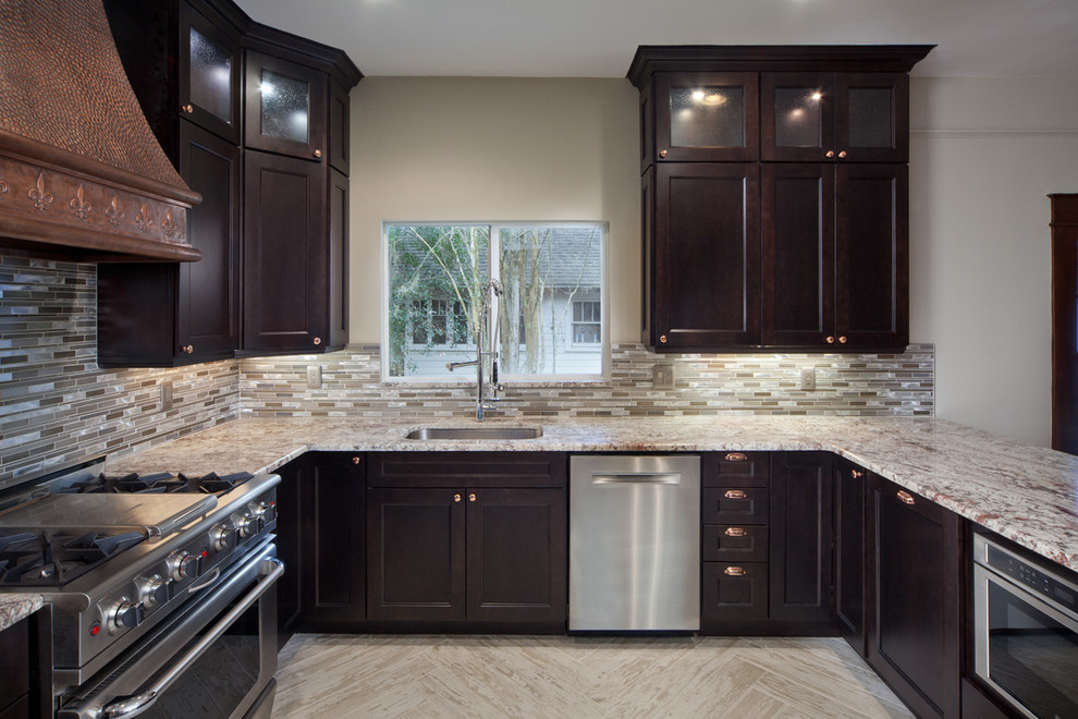 Photo of a mid-sized modern u-shaped eat-in kitchen in Orlando with dark wood cabinets, granite benchtops, metallic splashback, glass tile splashback, stainless steel appliances, an undermount sink, recessed-panel cabinets, ceramic floors and with island.