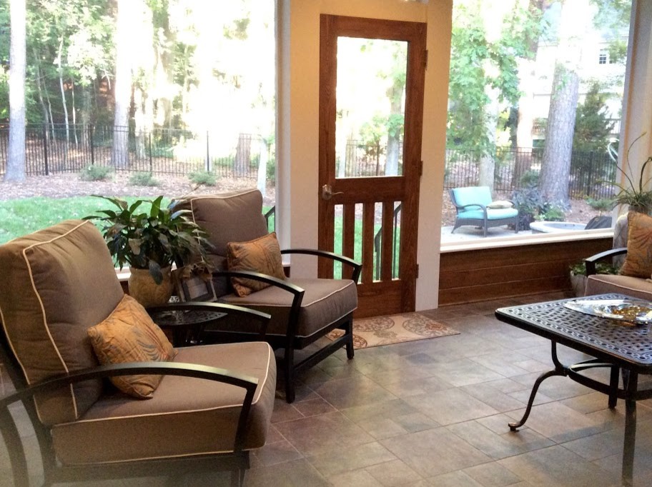 This is an example of a mid-sized transitional backyard screened-in verandah in Raleigh with a roof extension.