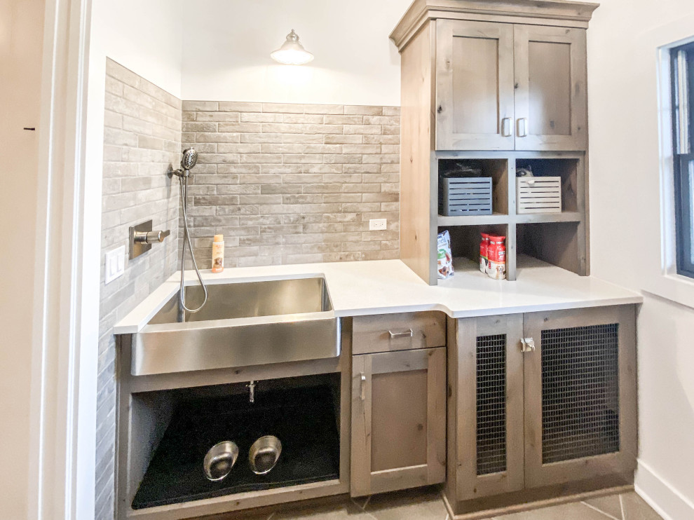 Dedicated laundry room - mid-sized industrial ceramic tile and gray floor dedicated laundry room idea in Chicago with a farmhouse sink, shaker cabinets, quartz countertops, white walls, a stacked washer/dryer and white countertops