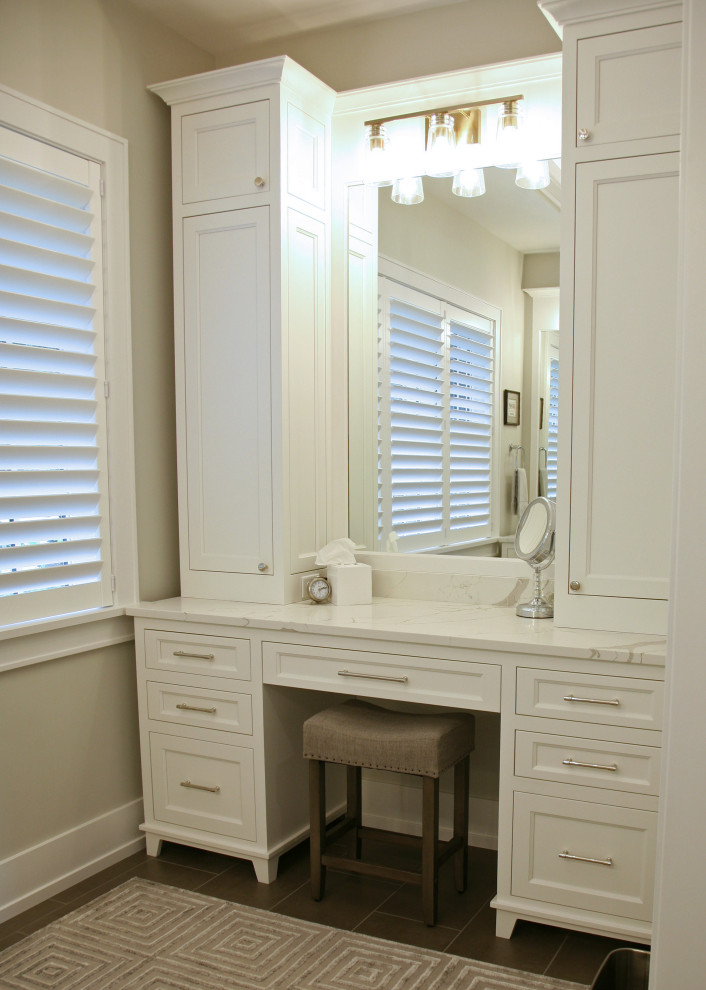 Inspiration for a mid-sized beach style bathroom in Milwaukee with shaker cabinets, white cabinets, a one-piece toilet, white tile, beige walls, porcelain floors, an undermount sink, engineered quartz benchtops, grey floor, a hinged shower door, white benchtops, a single vanity and a built-in vanity.