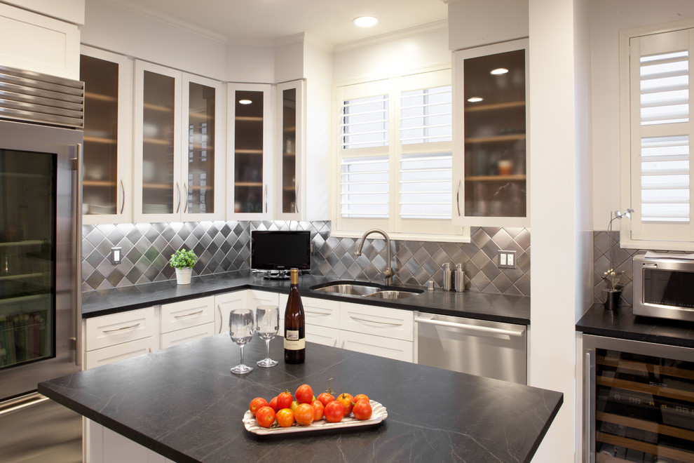 This is an example of a contemporary kitchen in San Francisco with a double-bowl sink, glass-front cabinets, white cabinets, soapstone benchtops, metallic splashback and metal splashback.
