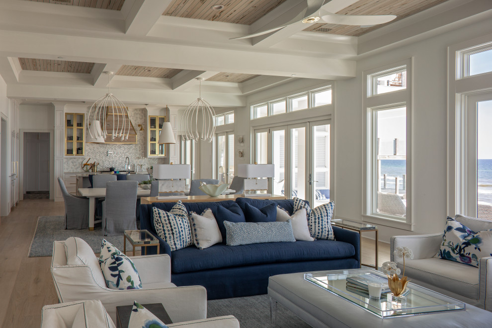 Inspiration for a large coastal open plan living room in Other with white walls, light hardwood flooring, a standard fireplace, a concrete fireplace surround, beige floors and a coffered ceiling.