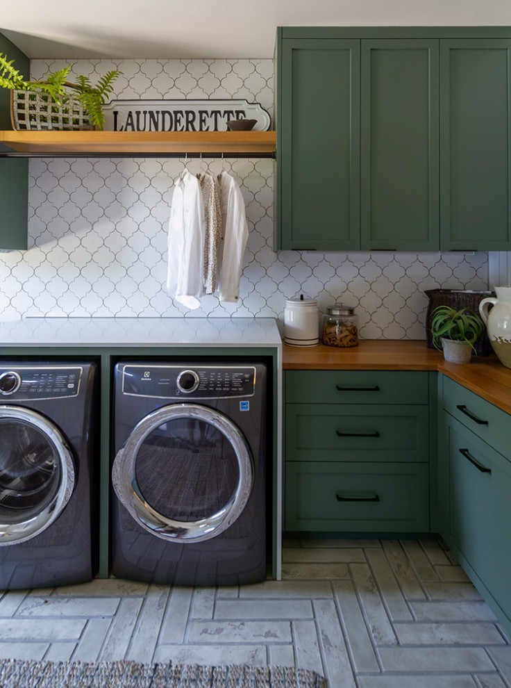 Inspiration for an expansive country l-shaped dedicated laundry room in Other with shaker cabinets, green cabinets, wood benchtops, white splashback, ceramic splashback, white walls, ceramic floors, a side-by-side washer and dryer, grey floor, brown benchtop and planked wall panelling.