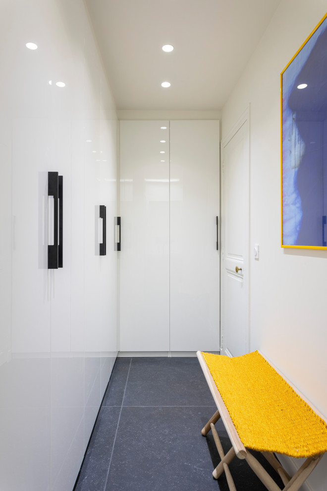 Cette photo montre un petit dressing room tendance neutre avec un placard à porte plane, des portes de placard blanches, un sol en ardoise et un sol gris.
