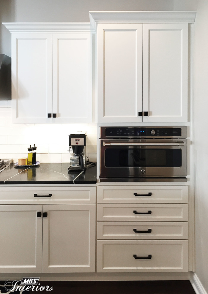 Mid-sized transitional u-shaped dark wood floor and brown floor eat-in kitchen photo with an undermount sink, recessed-panel cabinets, white cabinets, soapstone countertops, white backsplash, subway tile backsplash, stainless steel appliances and an island