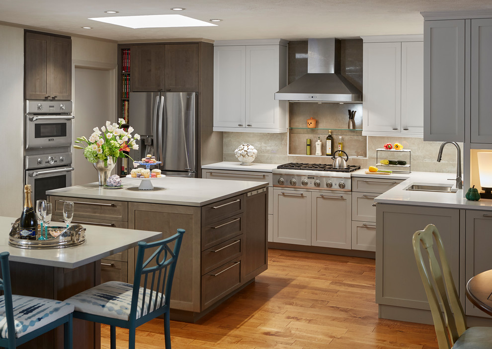 This is an example of a mid-sized traditional l-shaped eat-in kitchen in Dallas with shaker cabinets, stainless steel appliances, multiple islands, an undermount sink, white cabinets, quartz benchtops, grey splashback, stone tile splashback, dark hardwood floors, brown floor and white benchtop.