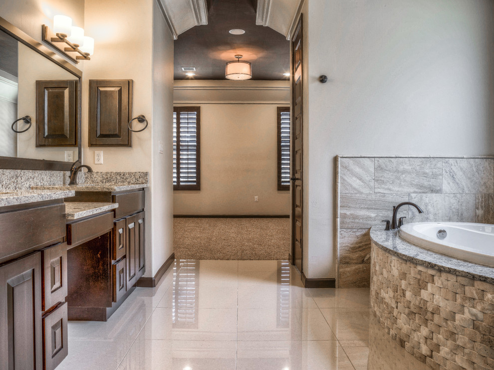 Photo of a mid-sized transitional master bathroom in Austin with raised-panel cabinets, dark wood cabinets, a drop-in tub, beige walls, an undermount sink, granite benchtops and a corner shower.