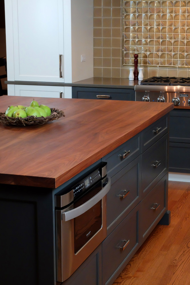 Inspiration for a large transitional u-shaped medium tone wood floor eat-in kitchen remodel in Chicago with shaker cabinets, wood countertops, stainless steel appliances, an island, an undermount sink, white cabinets, gray backsplash and stone tile backsplash