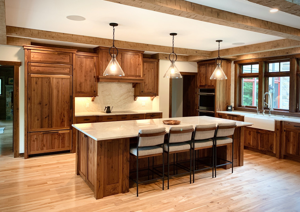Design ideas for a large arts and crafts u-shaped eat-in kitchen in Milwaukee with a farmhouse sink, recessed-panel cabinets, dark wood cabinets, quartzite benchtops, beige splashback, stone slab splashback, stainless steel appliances, medium hardwood floors, with island, brown floor, beige benchtop and exposed beam.