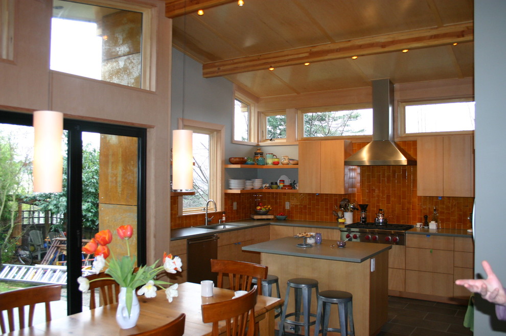 Photo of a mid-sized traditional u-shaped eat-in kitchen in Seattle with an undermount sink, flat-panel cabinets, light wood cabinets, solid surface benchtops, orange splashback, ceramic splashback, stainless steel appliances, porcelain floors and with island.