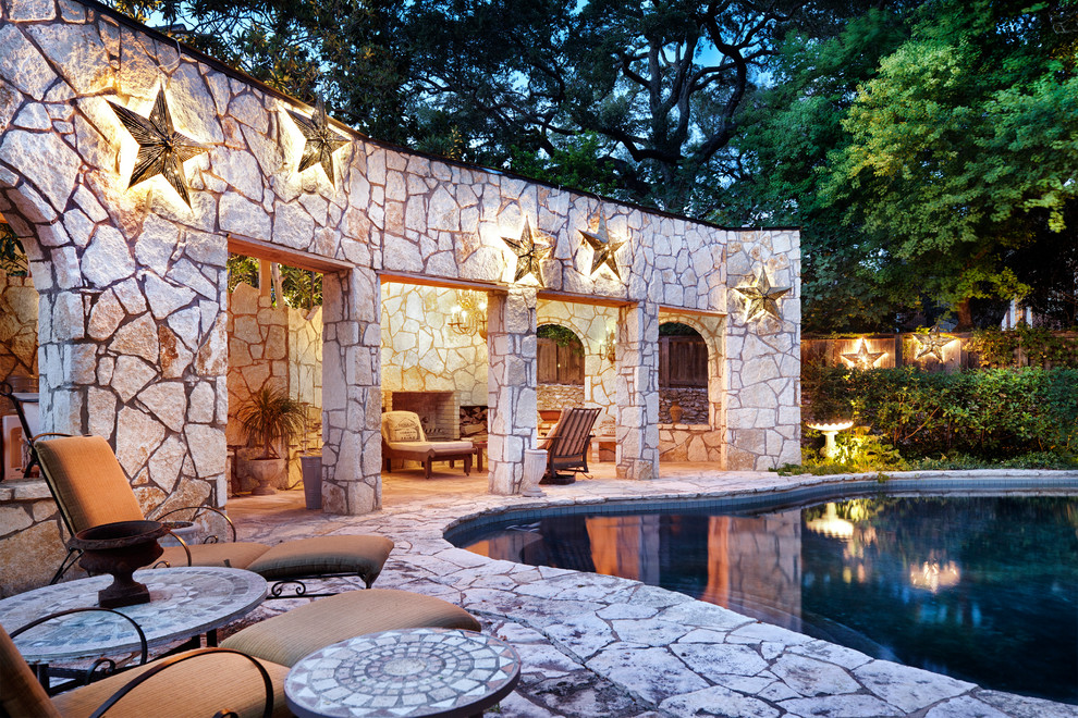 This is an example of an eclectic pool in Austin with natural stone pavers.