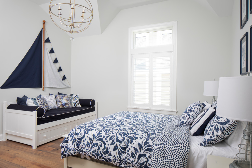 Design ideas for a beach style guest bedroom in New York with white walls, medium hardwood floors and brown floor.