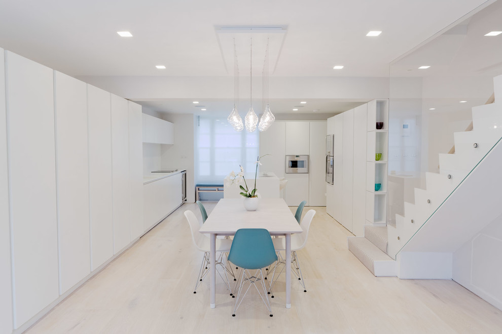 This is an example of a contemporary eat-in kitchen in London with flat-panel cabinets, white cabinets, light hardwood floors and with island.