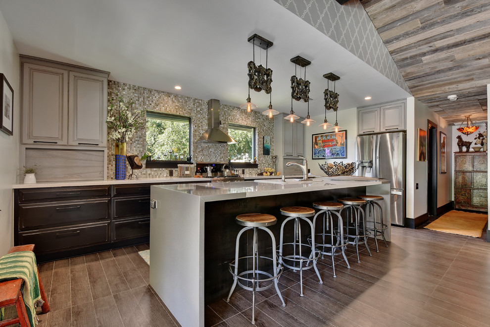 Photo of an eclectic kitchen in Austin with a drop-in sink, raised-panel cabinets, grey cabinets, multi-coloured splashback, mosaic tile splashback, stainless steel appliances and with island.