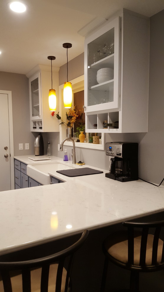 Mid-sized transitional u-shaped vinyl floor enclosed kitchen photo with a farmhouse sink, recessed-panel cabinets, blue cabinets, quartz countertops, stainless steel appliances and a peninsula