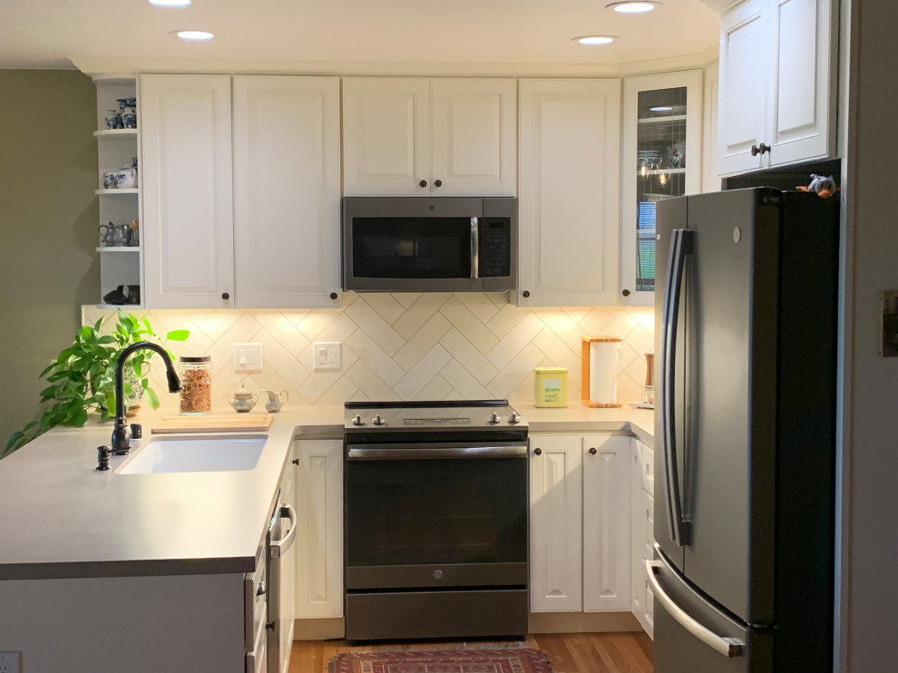 This is an example of a mid-sized transitional u-shaped eat-in kitchen in Sacramento with an undermount sink, raised-panel cabinets, white cabinets, quartzite benchtops, beige splashback, limestone splashback, stainless steel appliances, medium hardwood floors, brown floor and beige benchtop.