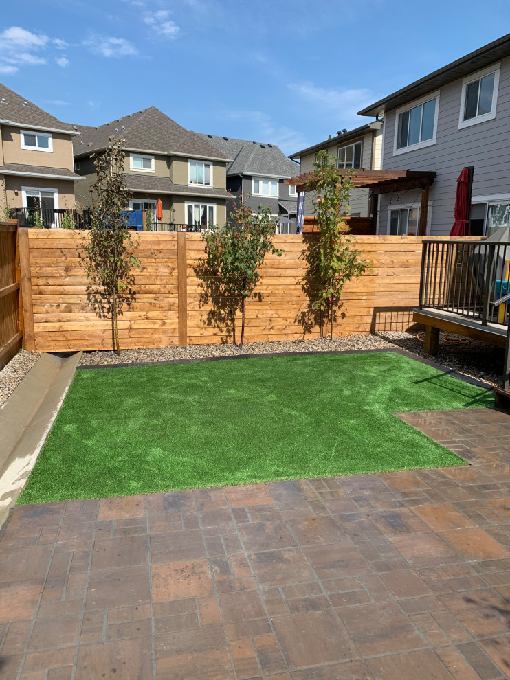 Small traditional back xeriscape and private full sun garden in Calgary with concrete paving.