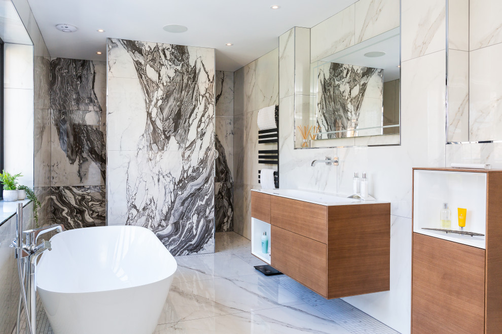 Modern inredning av ett vit vitt badrum, med släta luckor, skåp i mellenmörkt trä, ett fristående badkar, en kantlös dusch, ett integrerad handfat, vitt golv och med dusch som är öppen