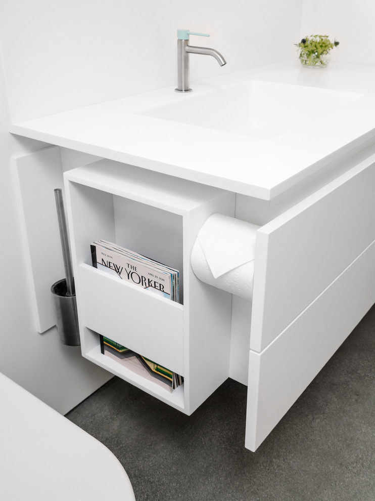 Modern bathroom in Other with white cabinets, an open shower, a wall-mount toilet, white tile, porcelain tile, white walls, concrete floors, an integrated sink, solid surface benchtops, grey floor, an open shower and white benchtops.