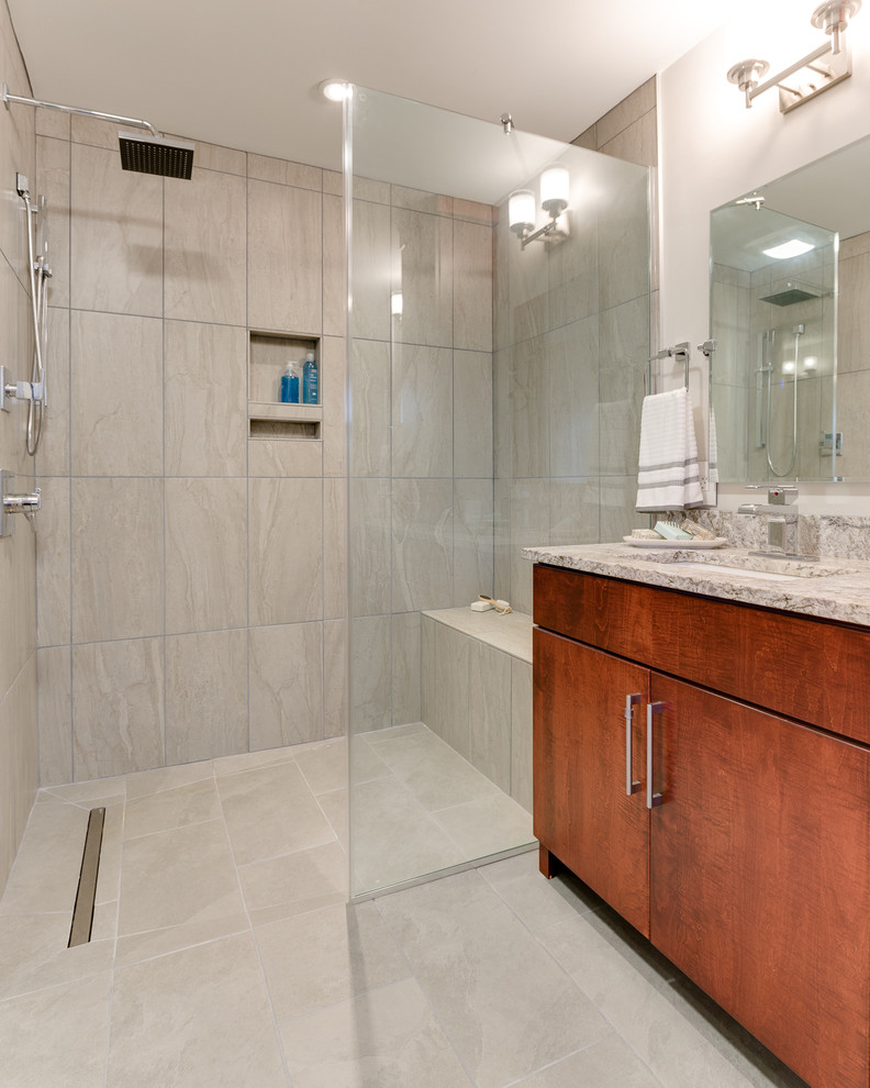 This is an example of a mid-sized contemporary master wet room bathroom in Columbus with flat-panel cabinets, medium wood cabinets, an undermount tub, a two-piece toilet, beige tile, gray tile, stone tile, white walls, light hardwood floors, a pedestal sink and granite benchtops.