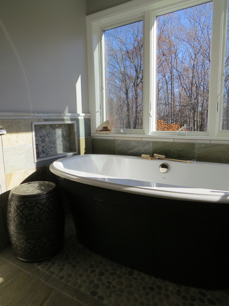Mid-sized beach style master bathroom in Portland Maine with furniture-like cabinets, grey cabinets, a freestanding tub, a curbless shower, a wall-mount toilet, multi-coloured tile, stone tile, multi-coloured walls, pebble tile floors, an undermount sink and engineered quartz benchtops.