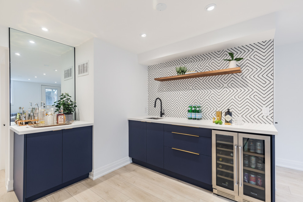 Photo of a small contemporary l-shaped wet bar in Toronto with vinyl floors, an undermount sink, flat-panel cabinets, blue cabinets, multi-coloured splashback, beige floor and white benchtop.