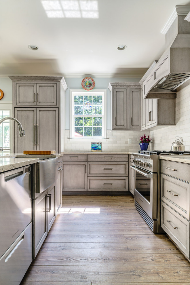 Mid-sized transitional l-shaped vinyl floor and brown floor eat-in kitchen photo with a farmhouse sink, gray cabinets, recycled glass countertops, multicolored backsplash, subway tile backsplash, stainless steel appliances, an island and multicolored countertops