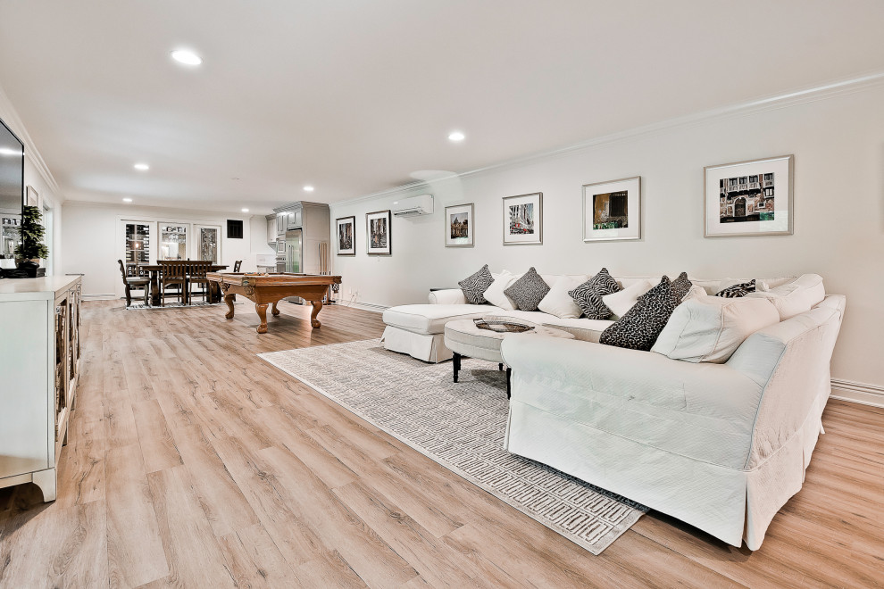 Inspiration for an expansive transitional walk-out basement in Other with a game room, white walls, laminate floors and brown floor.