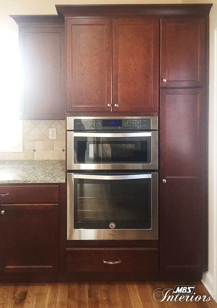 Example of a large transitional medium tone wood floor eat-in kitchen design in Cincinnati with an undermount sink, recessed-panel cabinets, dark wood cabinets, quartz countertops, beige backsplash, stone tile backsplash, stainless steel appliances and an island