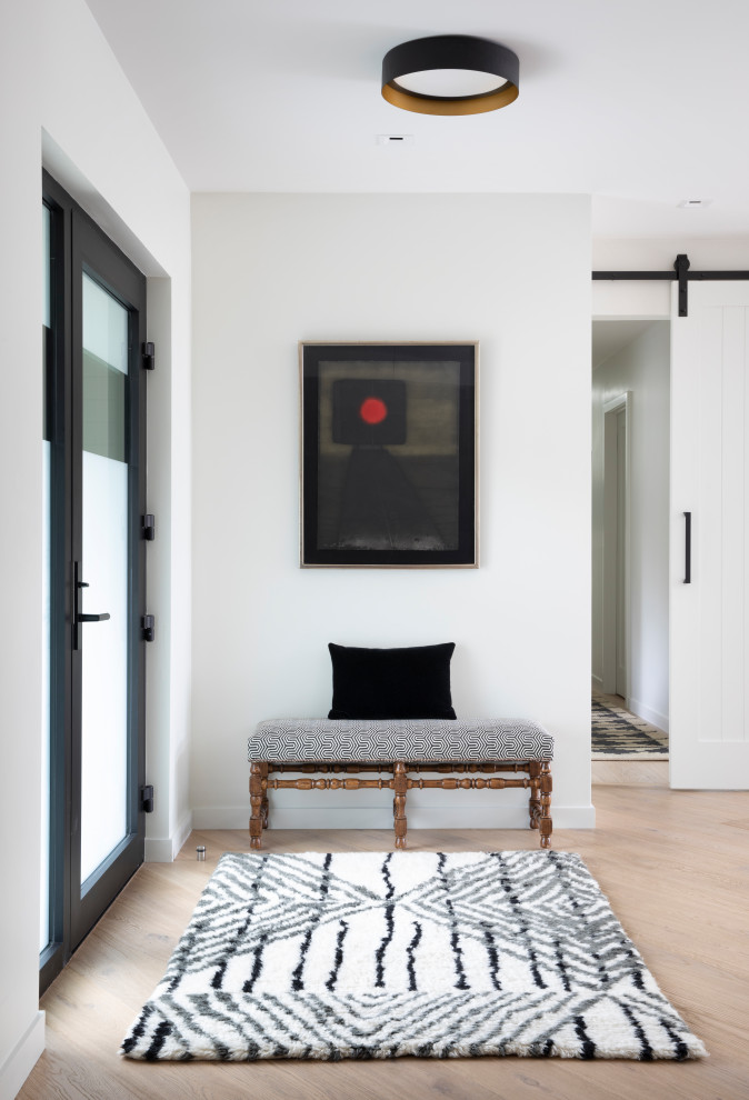 На фото: фойе среднего размера в скандинавском стиле с белыми стенами, светлым паркетным полом, одностворчатой входной дверью, металлической входной дверью и коричневым полом