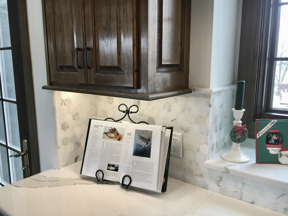 Example of a large transitional u-shaped medium tone wood floor open concept kitchen design with an undermount sink, recessed-panel cabinets, distressed cabinets, quartz countertops, multicolored backsplash, mosaic tile backsplash, stainless steel appliances and an island
